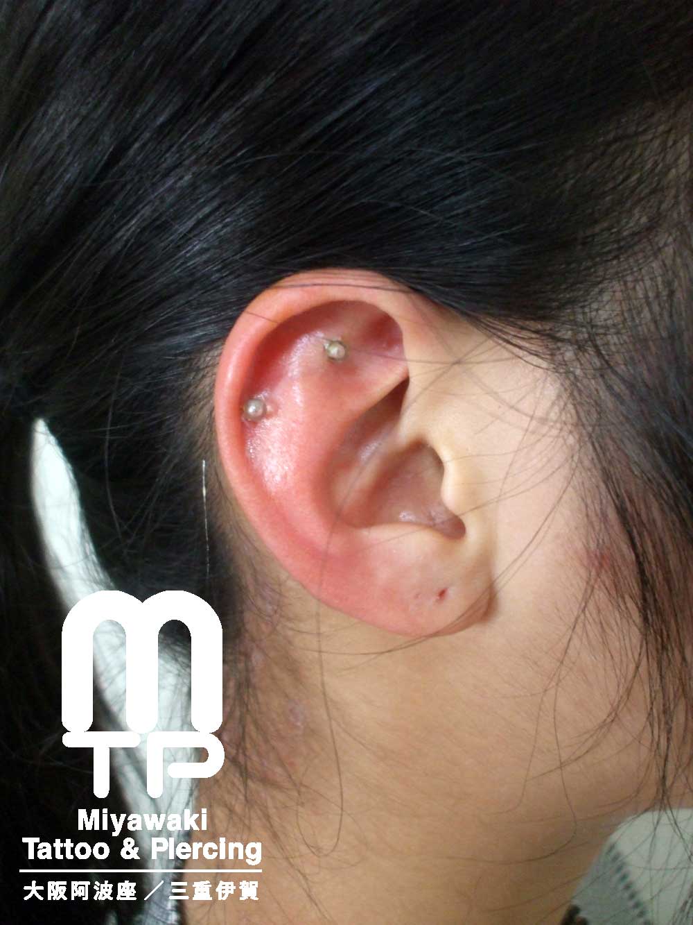 右耳の軟骨にアウターコンク、ヘリックスのピアスを目立たないように透明のキャッチを使用したピアス