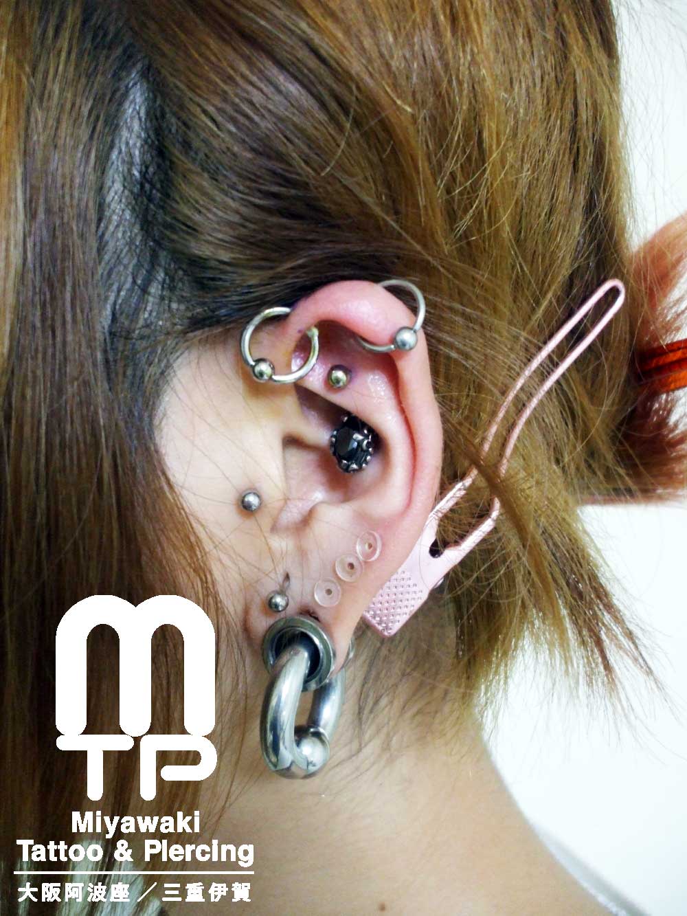 左耳に耳たぶはホールトゥでラージイヤーロブ、その他耳たぶに4カ所、軟骨はリングでヘリックスアンテナ、ロック、トラガスのピアス