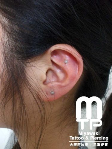 左耳の耳たぶ、軟骨のアウターコンクのピアスに目立たないように透明のキャッチを使用したピアス