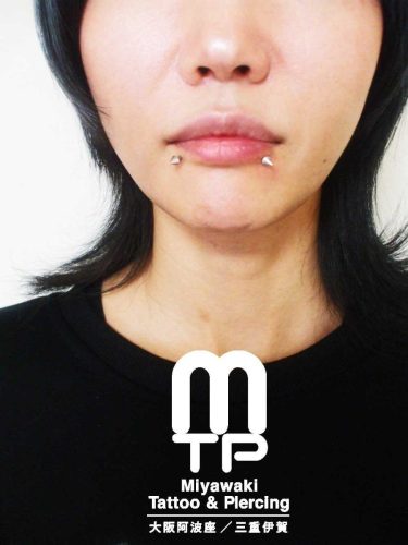 ピアスの部位及び名称　左右の下唇端に先の尖った（コーン）のキャッチでのリップピアス