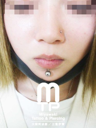 ピアスの部位及び名称　左小鼻にノストリルピアス、下唇中央に拡張されたラブレットピアス