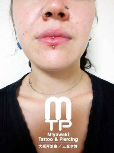 ピアスの部位及び名称　左小鼻にノストリルスクリュー、右小鼻にリングでのノストリルピアス、下唇中央に唇中心を縦に貫通したヴァーティカルリップピアス