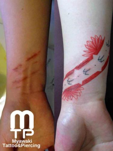 手首の傷の流れに併せて、赤いポリネシアンデザインのタトゥー