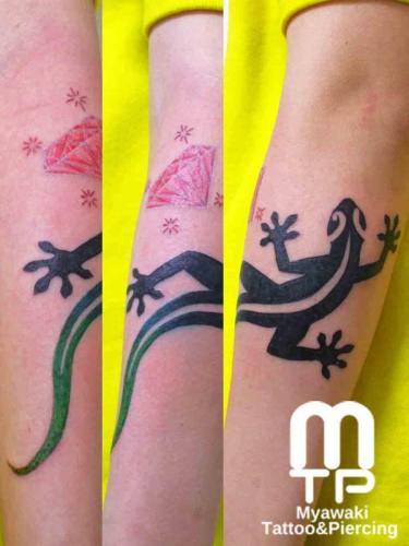 腕に尻尾が緑のグラデーションでのトライバルデザインでのゲコとピンクのダイヤモンド。