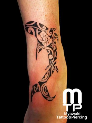 脛にポリネシアンデザインの鮫のタトゥー