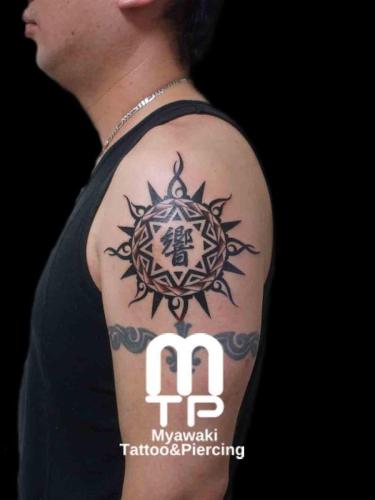 二の腕に漢字を中心とした太陽をイメージしたポリネシアンデザインのタトゥー