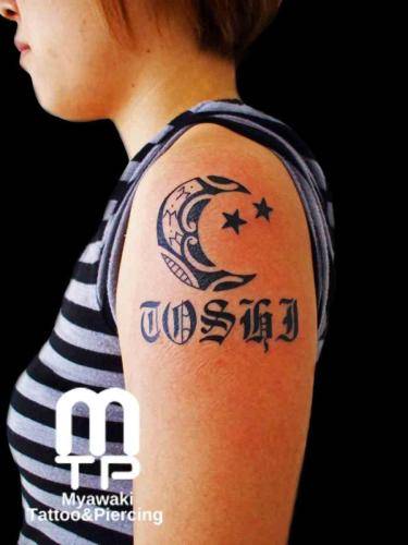 二の腕に、三日月のデザインでのポリネシアンデザインのタトゥー