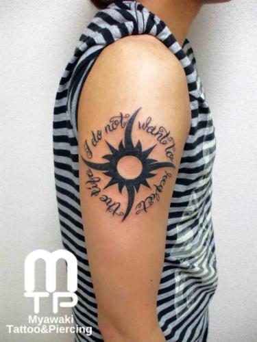 腕にトライバルデザインの太陽。周囲を囲むように英文字