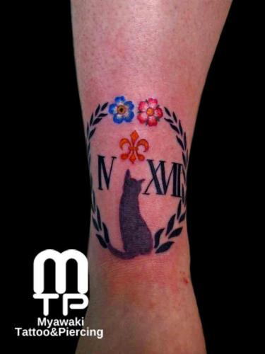 足首後ろに薄墨での猫のシルエット、ローマ数字を取り囲むように、赤と青の花や蔦での装飾